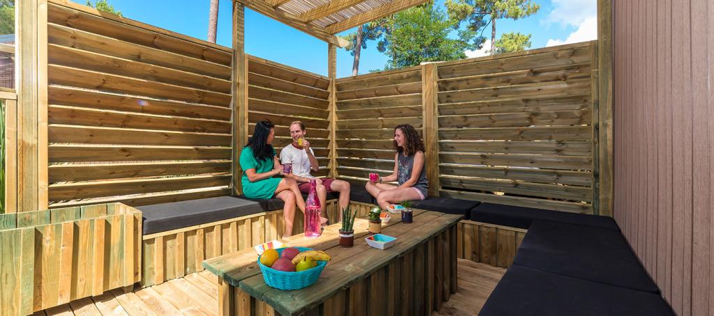 Des amis prennent l'apéritifs sur la terrasse d'un mobil home haut de gamme au cap ferret